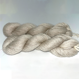 Two hanks of twisted yarn in a soft oatmeal beige color, arranged on a light gray and white background.