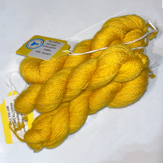 Three skeins of bright yellow fingering yarn with paper labels, arranged on a white background.