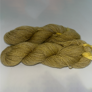 Two skeins of twisted yarn in a warm mustard-gold color with subtle yellow highlights, photographed on a plain light background.