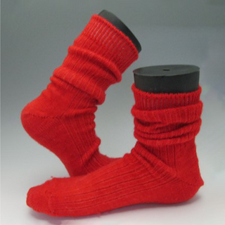 A pair of bright red ribbed knit socks displayed on black cylindrical mannequin legs against a neutral gray studio background.