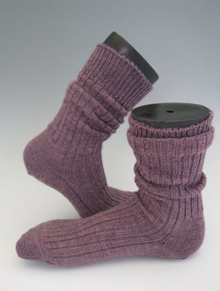 A pair of ribbed knit ankle socks in a dusty mauve-purple color, displayed on black sock hangers against a light gray gradient background.
