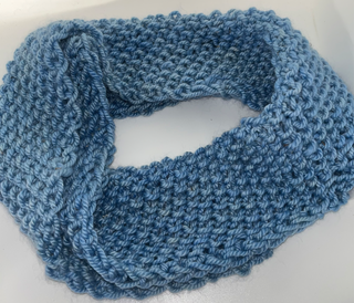 A light blue chunky-knit infinity scarf or cowl, shown draped on a plain white surface.