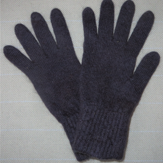 A pair of dark purple knit gloves laid flat on a light gray textured fabric background.