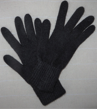 A pair of black knit gloves with ribbed cuffs, laid flat on a light gray textured fabric background.
