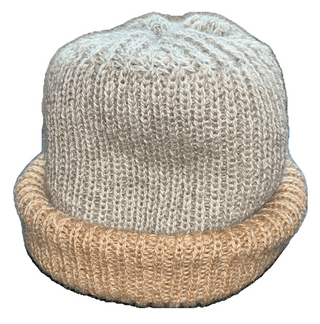 A hand-knit beanie hat featuring a light gray upper section and a contrasting tan ribbed brim, shown against a plain white background.