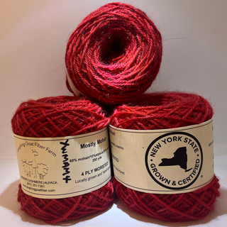 Three skeins of red yarn stacked together, with labels showing 'Mostly Mohair' and 'New York State Grown & Certified' by Laughing Goat Fiber Farm.