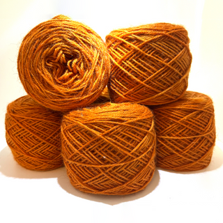 Five skeins of warm orange yarn stacked together on a white background.