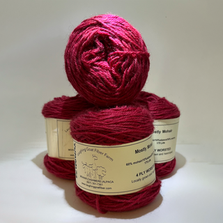 Three balls of deep FUSCHIA yarn stacked together, with labels visible on the sides. The labels read 'Laughing Goat Fiber Farm' and 'Mostly Mohair'.